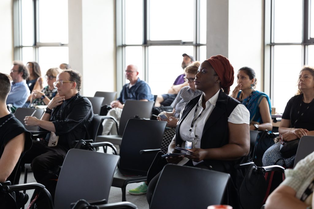 attendees sat on chairs in a bright room listening to a session