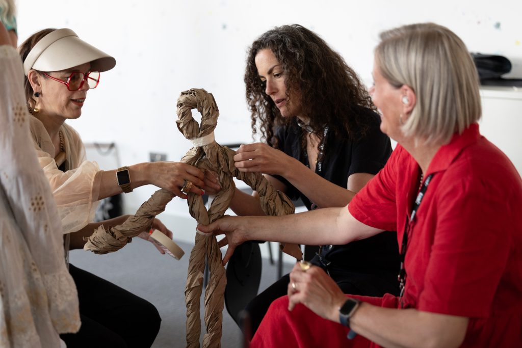 participants manipulating a paper structure in a shape of a human